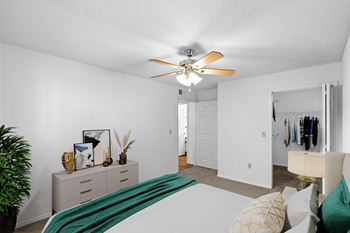 A bedroom with a large bed and a ceiling fan